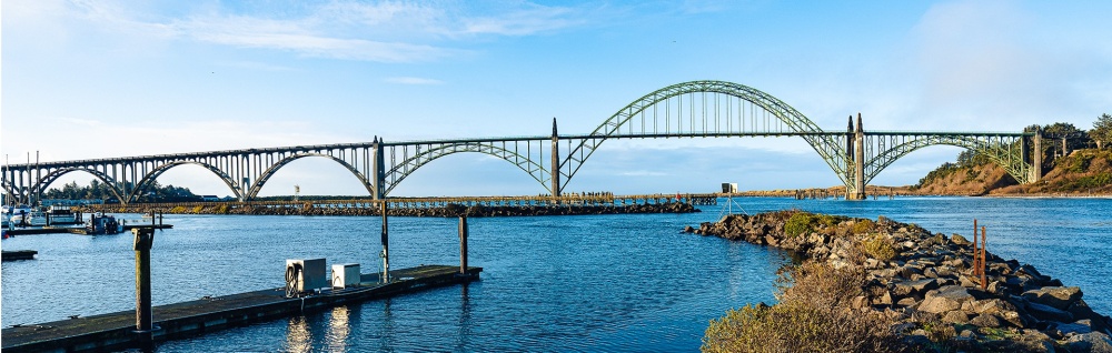 Yaquina Bay Bridge in Newport, OR stands proudly over the Pacific Ocean on a bright sunny day.